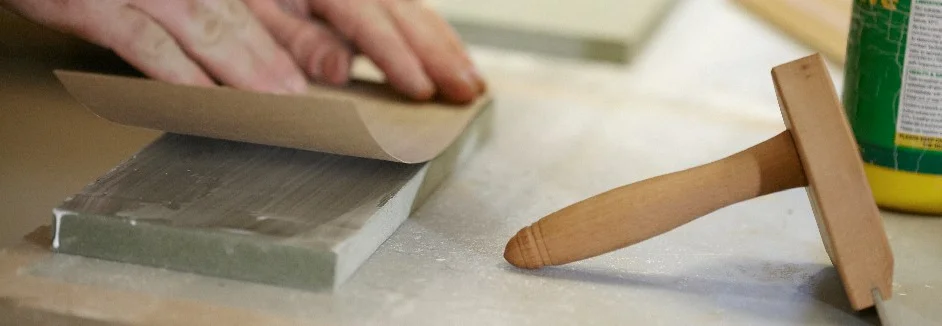 Person schleift Holz mit Schleifpapier